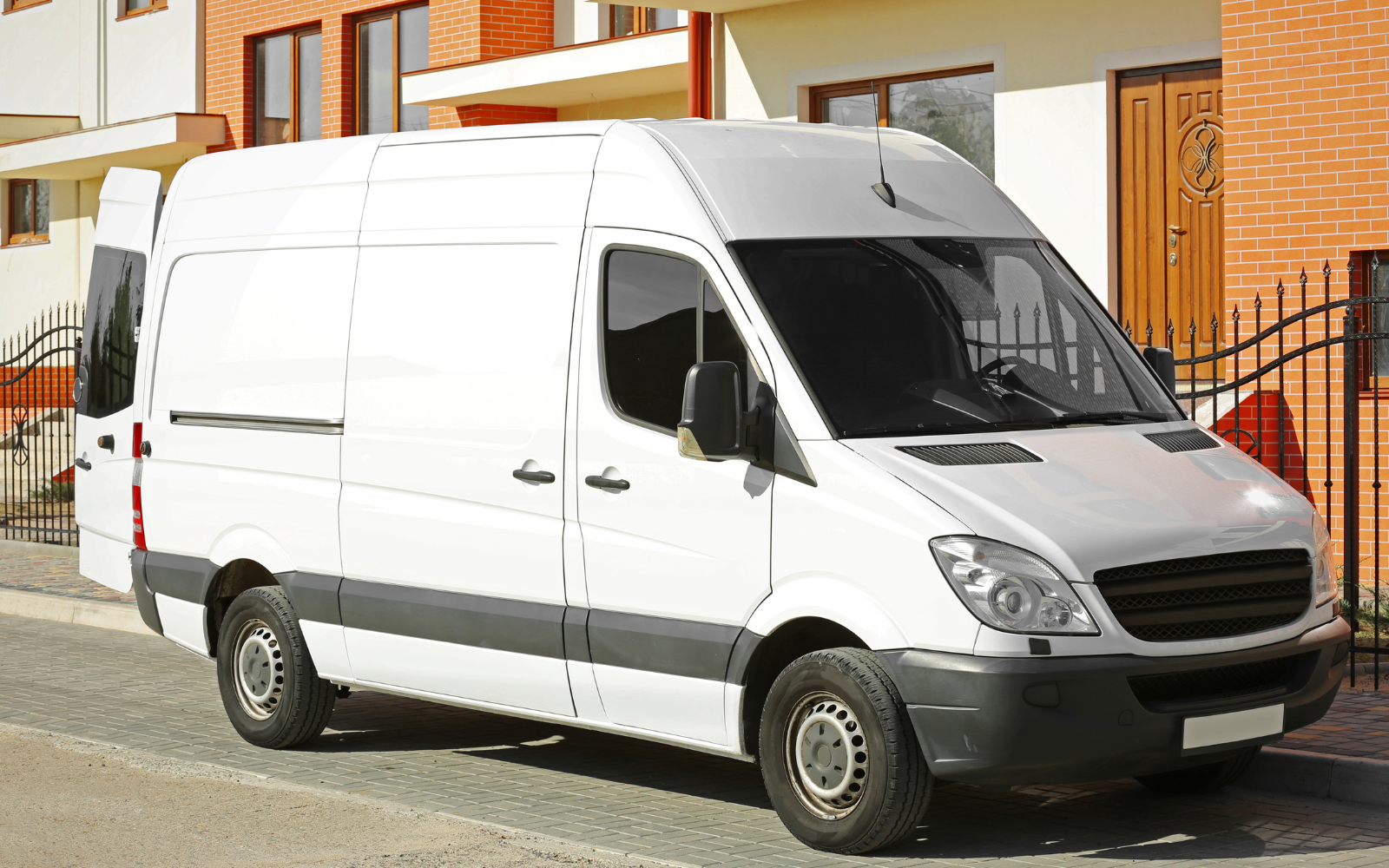 A white works van parked on the street outside a building.