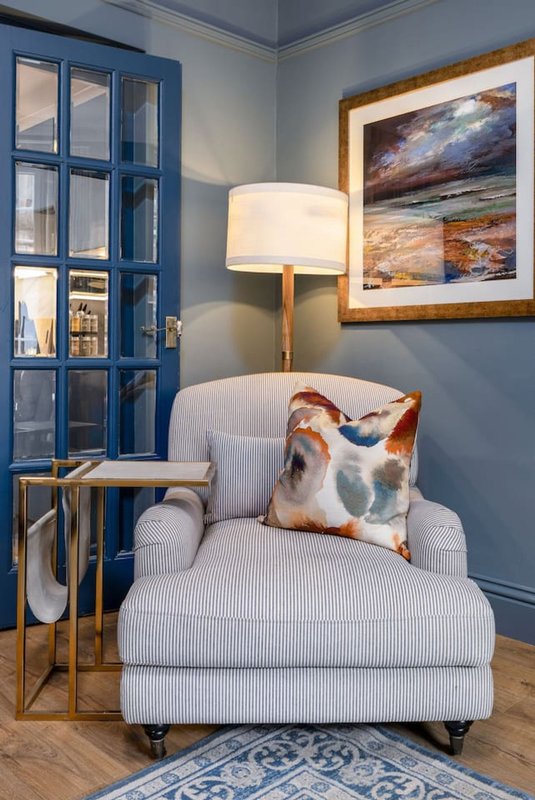Cozy reading nook with upholstered armchair, floor lamp, decorative pillow and framed artwork