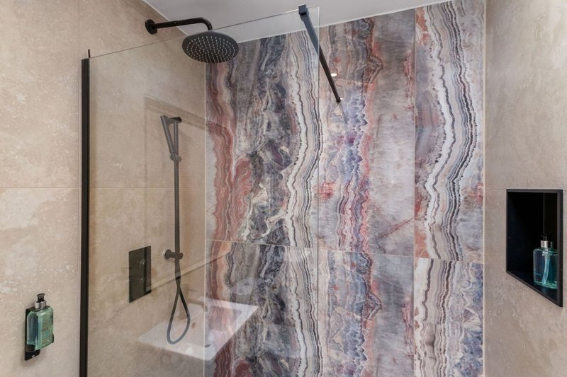 Modern bathroom with walk-in shower, rainfall showerhead, and decorative tile wall