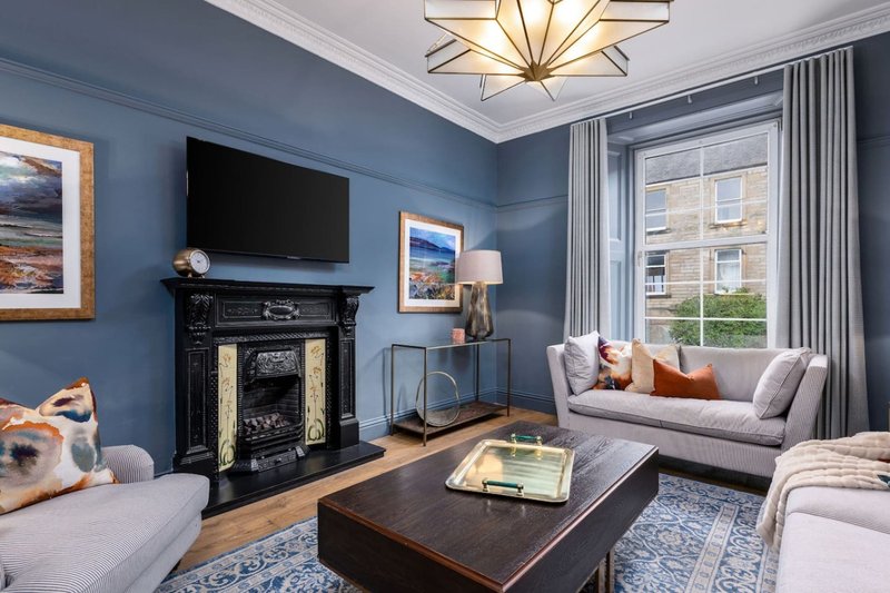 Contemporary living room with blue walls, fireplace, TV, sofa and armchairs