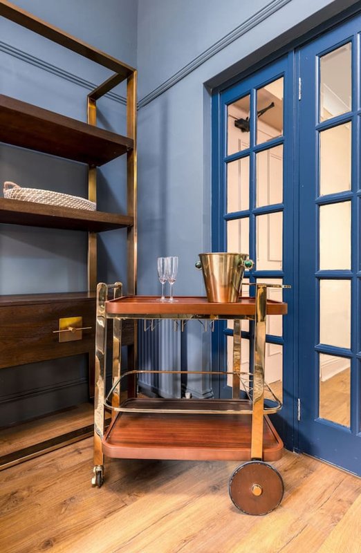 Modern interior with wooden shelving, blue glass doors, and serving cart by window