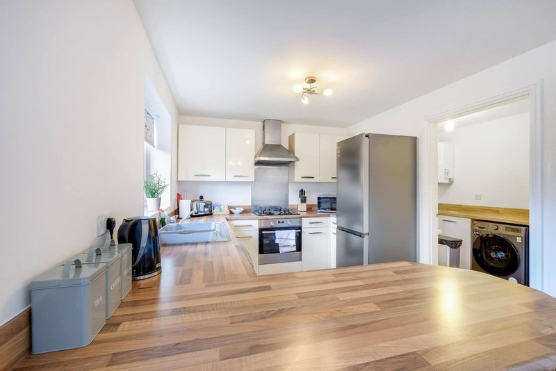 Modern kitchen with wooden countertop, white cabinetry, stainless steel appliances and dining area