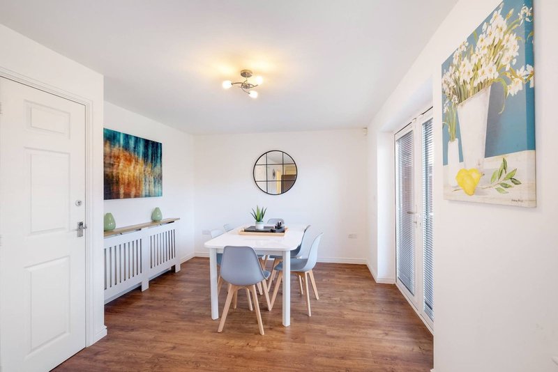 Bright dining room with white table, blue chairs, wooden floor and wall art