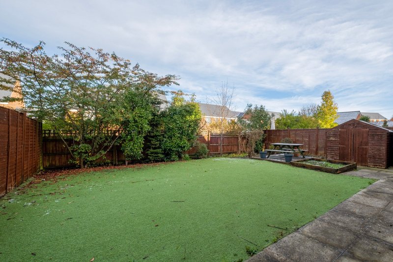 Spacious garden with lawn, wooden fences, trees and patio area