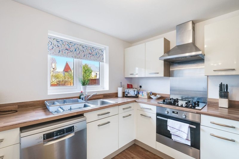 Modern kitchen with white cabinets, wooden worktops, stainless steel appliances and window