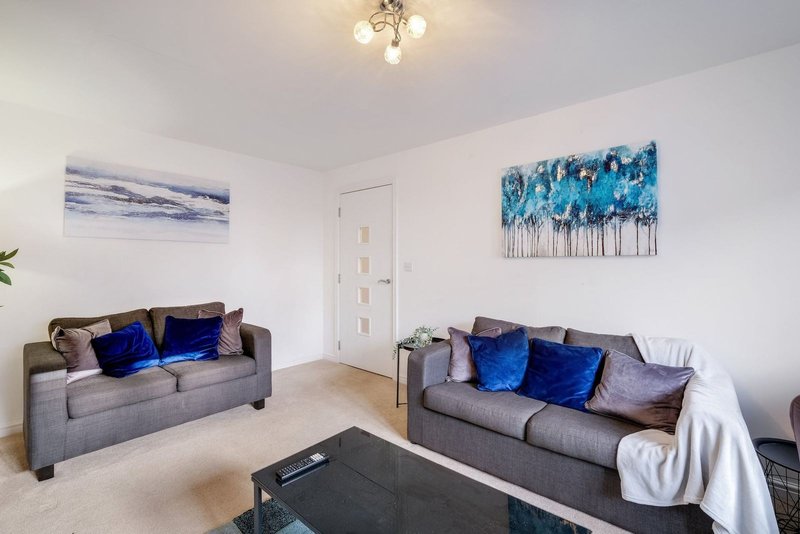Modern living room with two gray sofas, blue cushions, coffee table and framed wall art