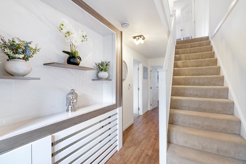 Modern hallway with staircase, white shelving with potted plants, wood flooring