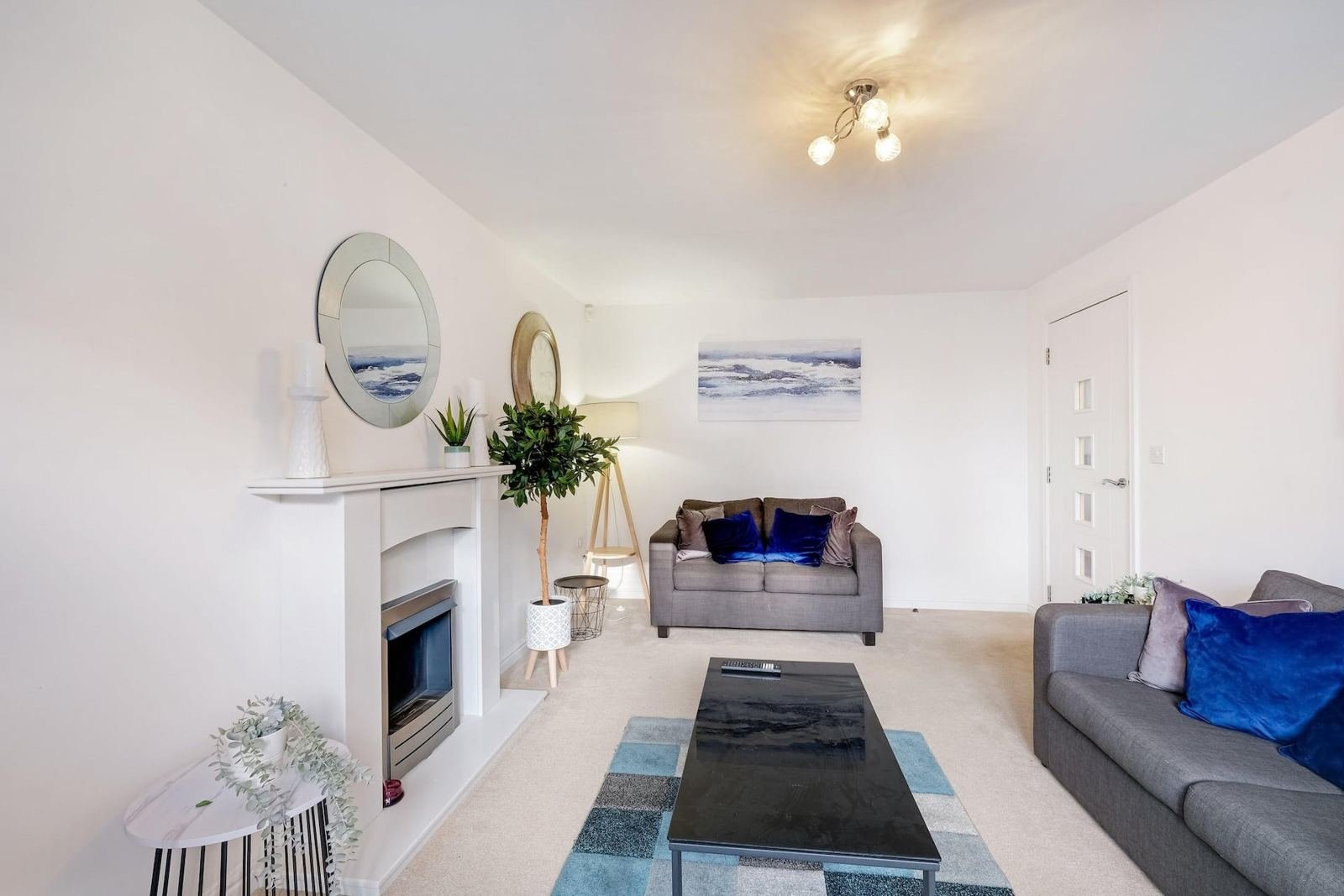 Modern living room with fireplace, grey sofas, blue cushions and contemporary artwork