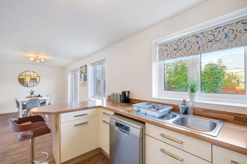 Modern kitchen with cream cabinets, wooden worktops, stainless steel appliances and garden views