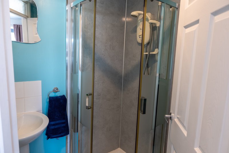 Modern bathroom with turquoise walls, glass shower enclosure, sink and towel rack