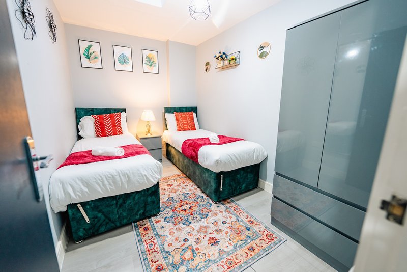 Bright twin bedroom with two single beds, colorful bedding, wall art, and sliding wardrobe