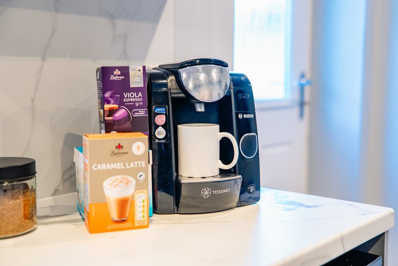 Kitchen counter with coffee maker, branded beverage boxes, and glass jar