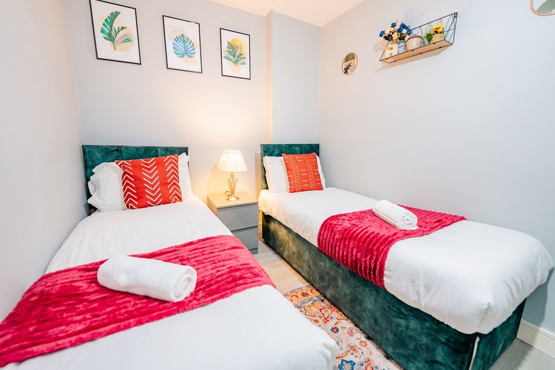 Bright twin bedroom with teal headboards, white bedding, pink throws, and colorful wall art