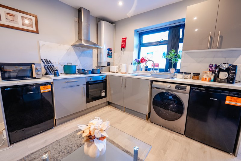 Modern kitchen with white and black cabinetry, stainless steel appliances, and blue door to garden