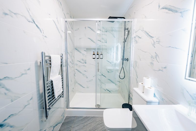 Modern bathroom with marble-effect tiling, glass shower enclosure and white fixtures