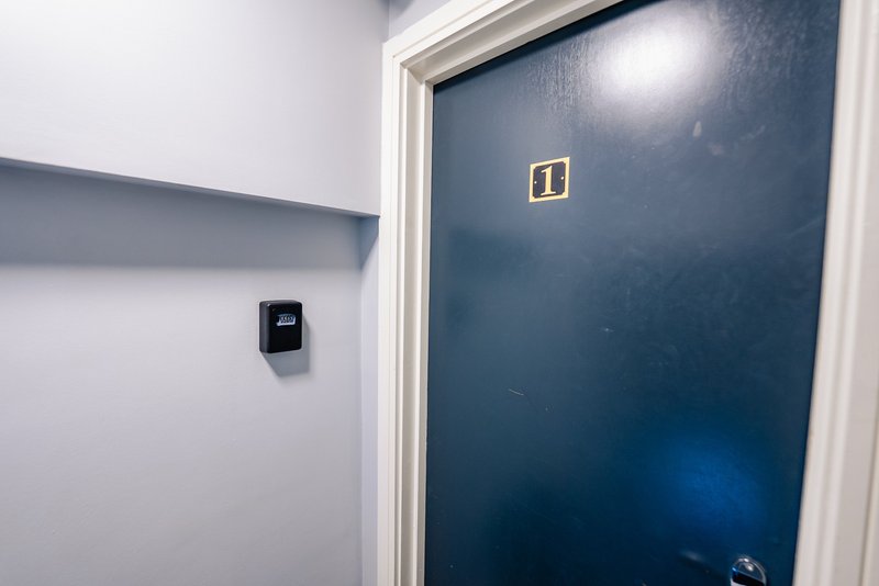 Modern hallway with white and dark blue walls, light switch, and closed door