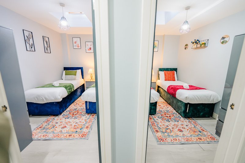 Two single beds in separate rooms with colorful bedding, patterned rugs, and pendant lighting