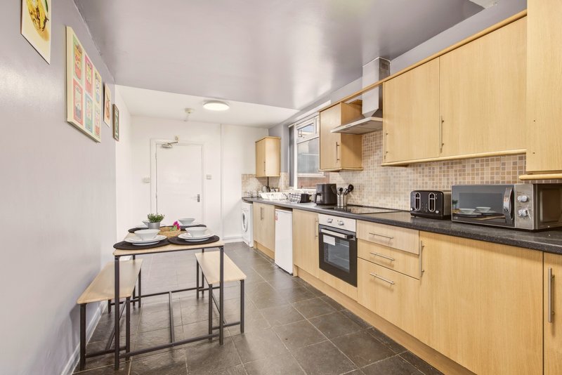 Modern kitchen with light wood cabinets, black countertops, dining table and stainless steel appliances