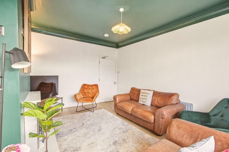 Living room with cognac leather sofa, armchair, pendant light, potted plant and fireplace