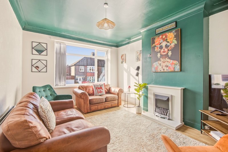 Bright living room with turquoise ceiling, brown leather sofas, fireplace and large windows overlooking street