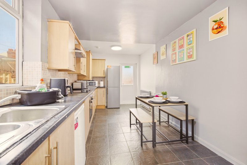Modern kitchen with light wood cabinets, stainless steel appliances, and dining table