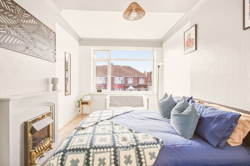 Bright bedroom with double bed, blue bedding, wooden floor and street view from window