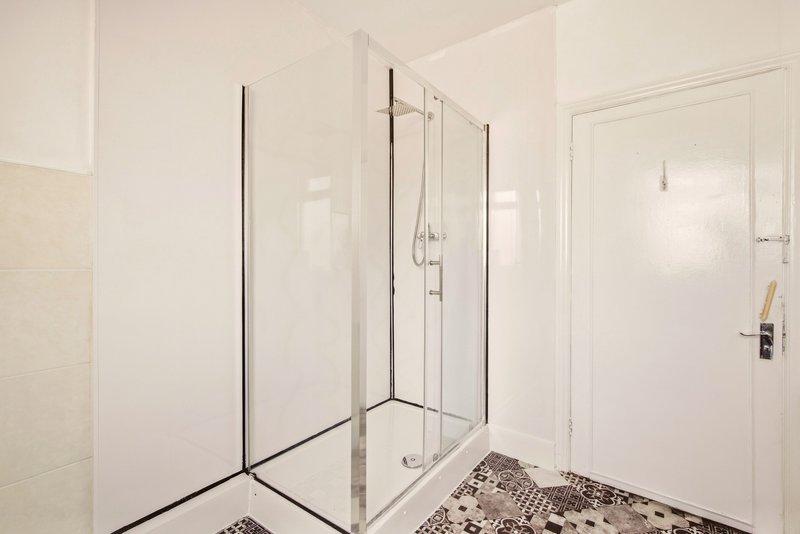 Modern bathroom with frameless glass shower enclosure and patterned tile floor