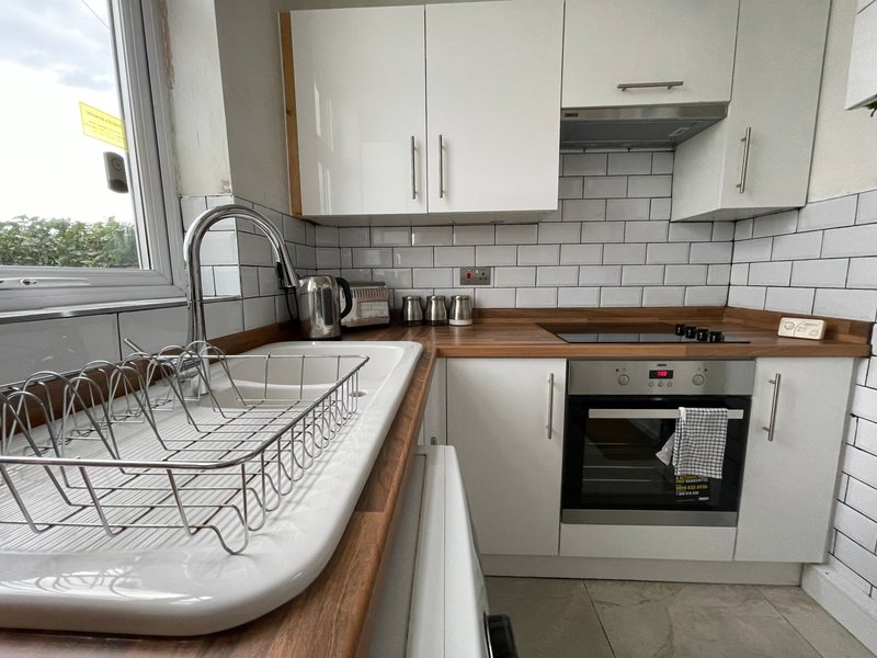 Modern kitchen with white cabinetry, subway tile backsplash, wooden countertops and built-in oven