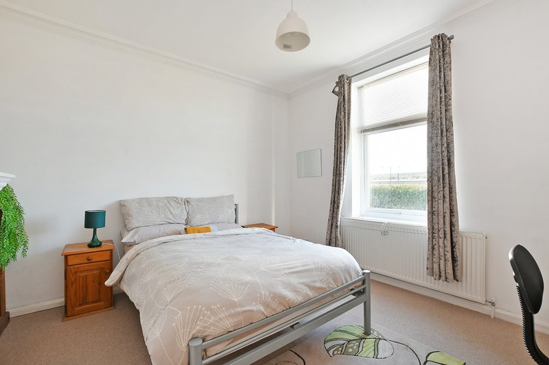 Bright bedroom with double bed, wooden nightstand, pendant light and large window with curtains