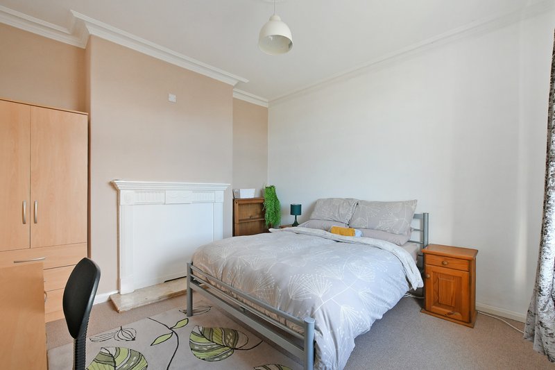 Bright bedroom with double bed, wooden wardrobes, desk chair and pendant light