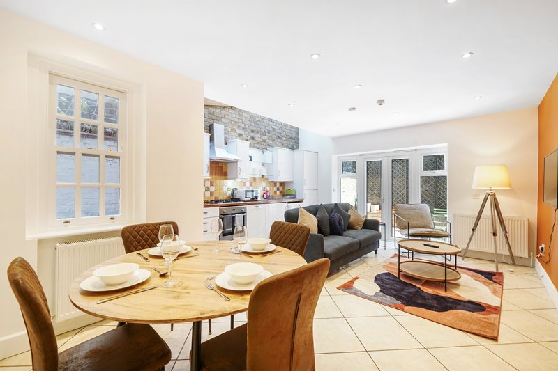 Open-plan kitchen-diner and lounge with wooden dining table, tan leather chairs, and modern furnishings