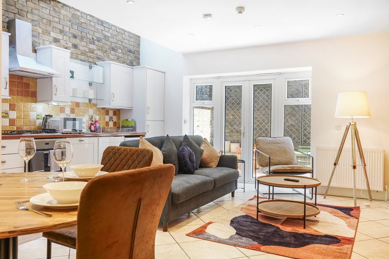 Open-plan kitchen and living room with leather sofa, dining table, and patio doors