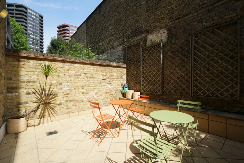 Outdoor patio with seating area, potted plants, brick walls and city views
