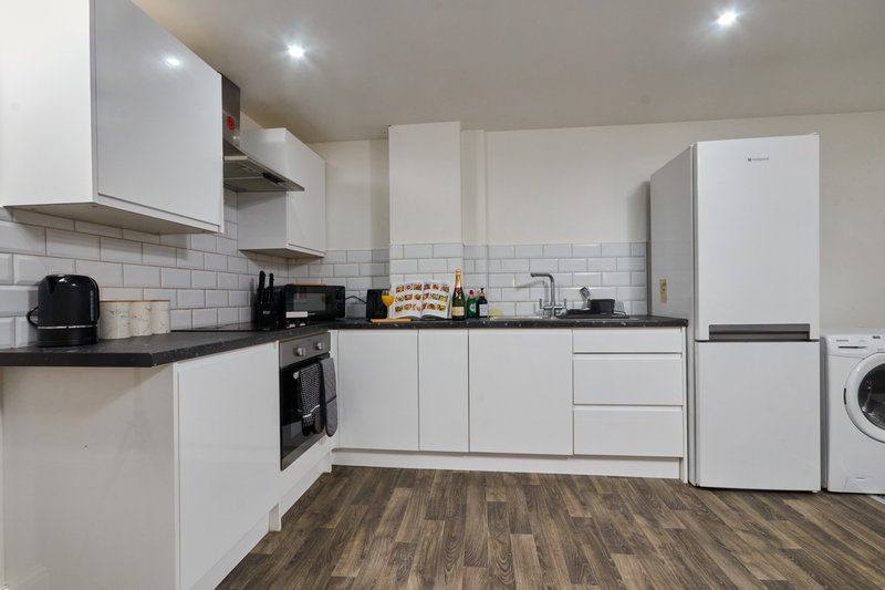 Modern kitchen with white cabinetry, black countertops, subway tile splashback, and integrated appliances