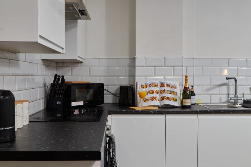 Modern kitchen with white subway tiles, black countertop, white cabinetry and stainless steel tap