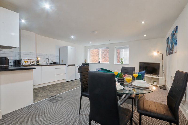 Open-plan kitchen and dining area with white cabinetry, dining table, and seating