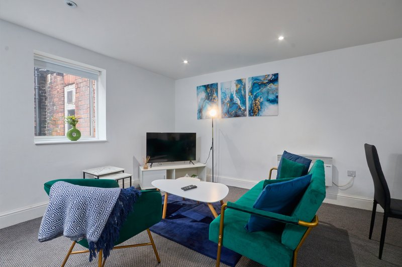 Modern living room with green armchair, TV, white coffee table and blue artwork