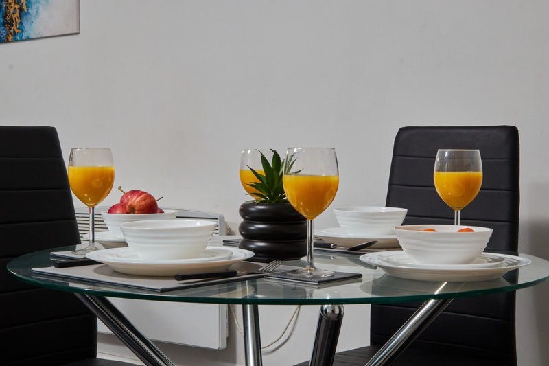 Modern dining table set with glasses of juice, place settings, and fruit centerpiece