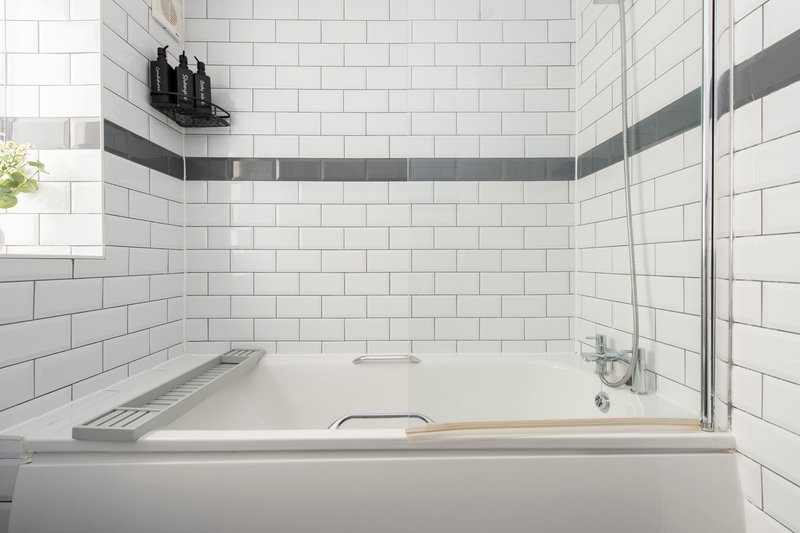 Modern bathroom with white subway tile walls, bathtub with shower screen and chrome fixtures