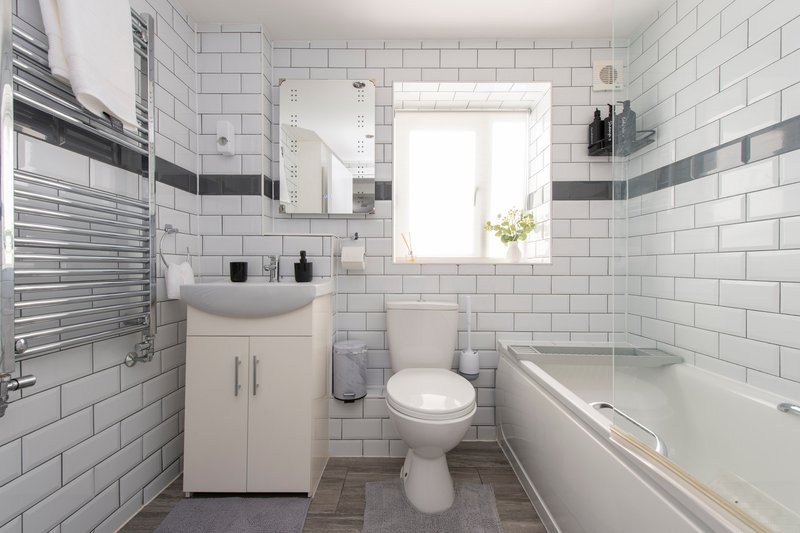 Modern bathroom with white subway tiles, vanity sink, toilet, bathtub and mirror