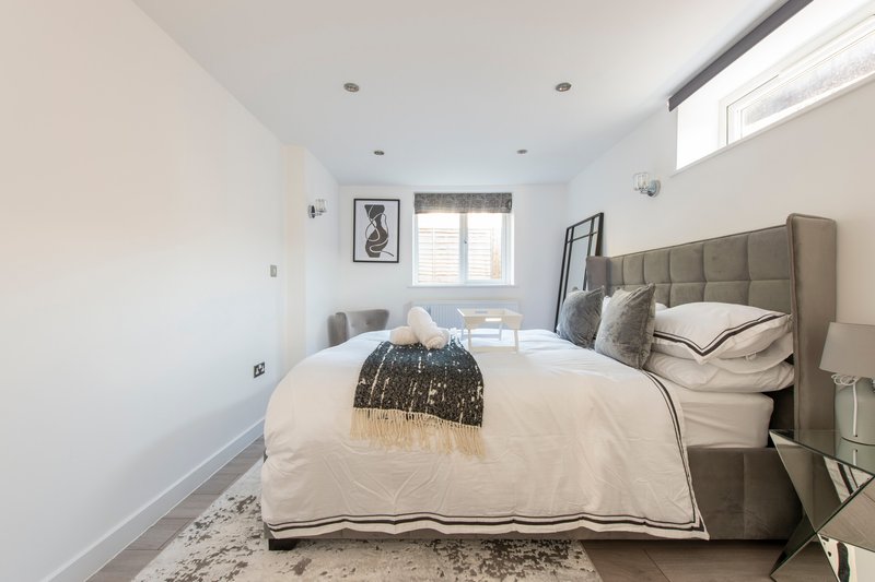 Modern bedroom with upholstered headboard, white bedding, and framed wall art