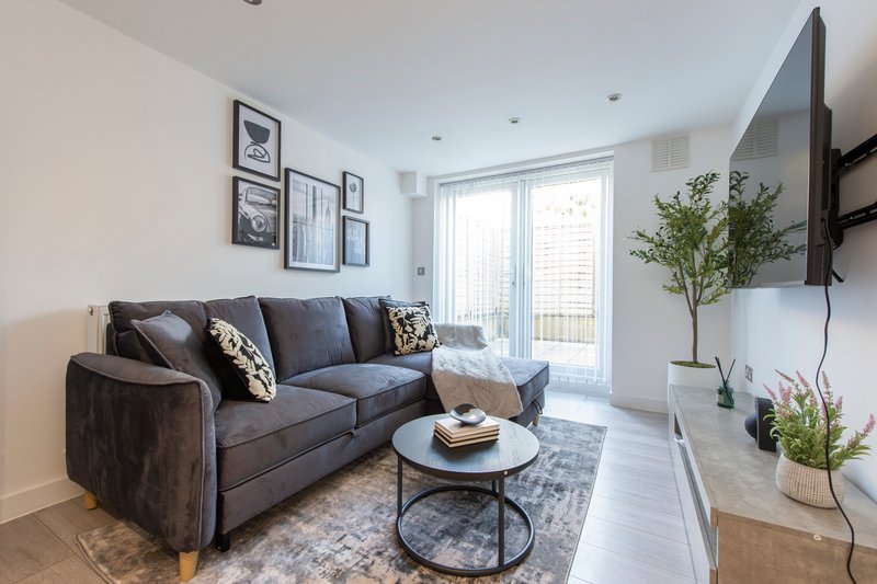 Modern living room with grey sofa, round coffee table, framed wall art, and TV mounted on right wall