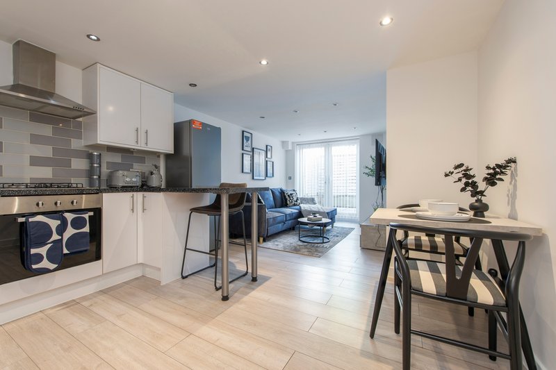 Open-plan kitchen and living area with white cabinetry, dining table, and blue sofa