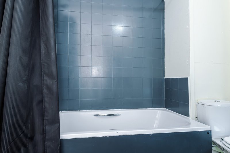 Modern bathroom with blue tile walls, white bathtub and toilet