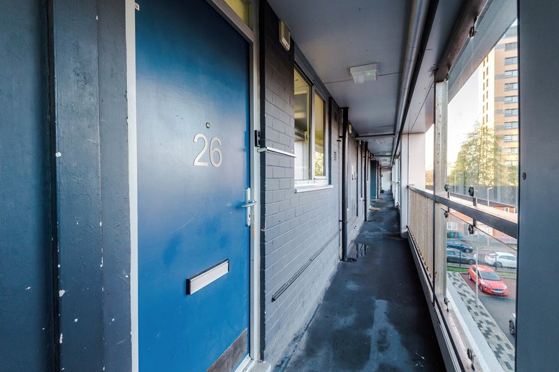 Exterior corridor with blue numbered door and mailbox, modern apartment building hallway