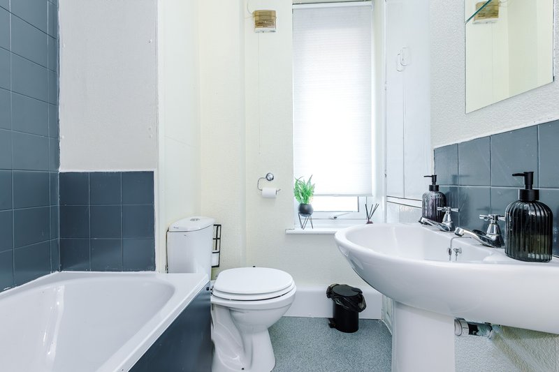 Modern bathroom with white suite, tiled walls, pedestal sink and bathtub