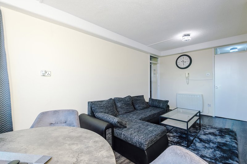 Living room with dark corner sofa, coffee table, wall clock and cream walls
