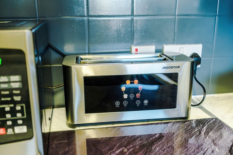 Kitchen counter with stainless steel microwave oven and teal tile backsplash
