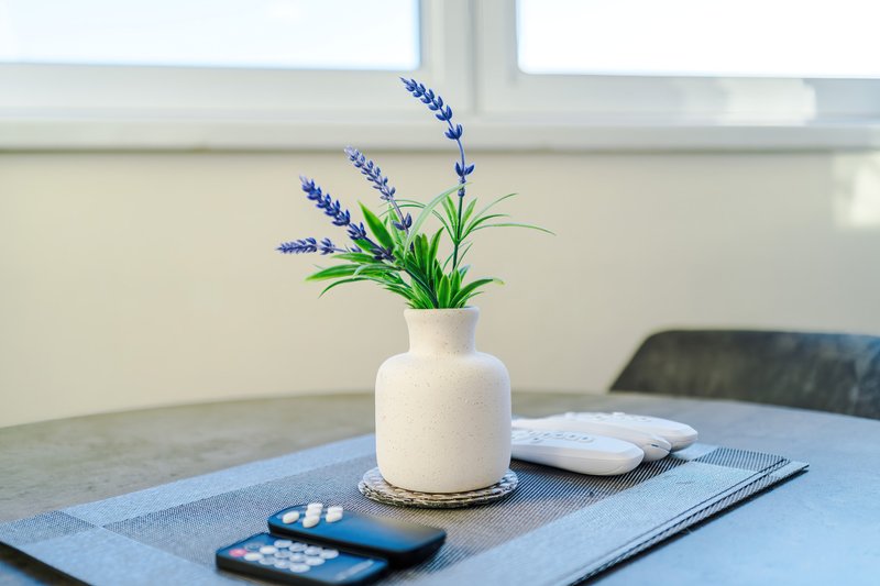 Modern desk with white vase of purple flowers, laptop, and smartphone