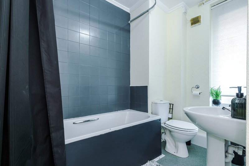 Modern bathroom with bathtub, shower enclosure, toilet, pedestal sink and tiled walls